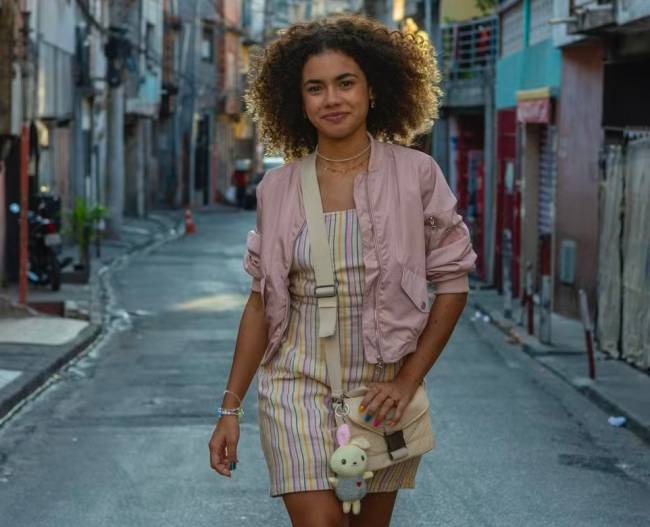 Foto da atriz Alana Cabral caracterizada e andando na rua