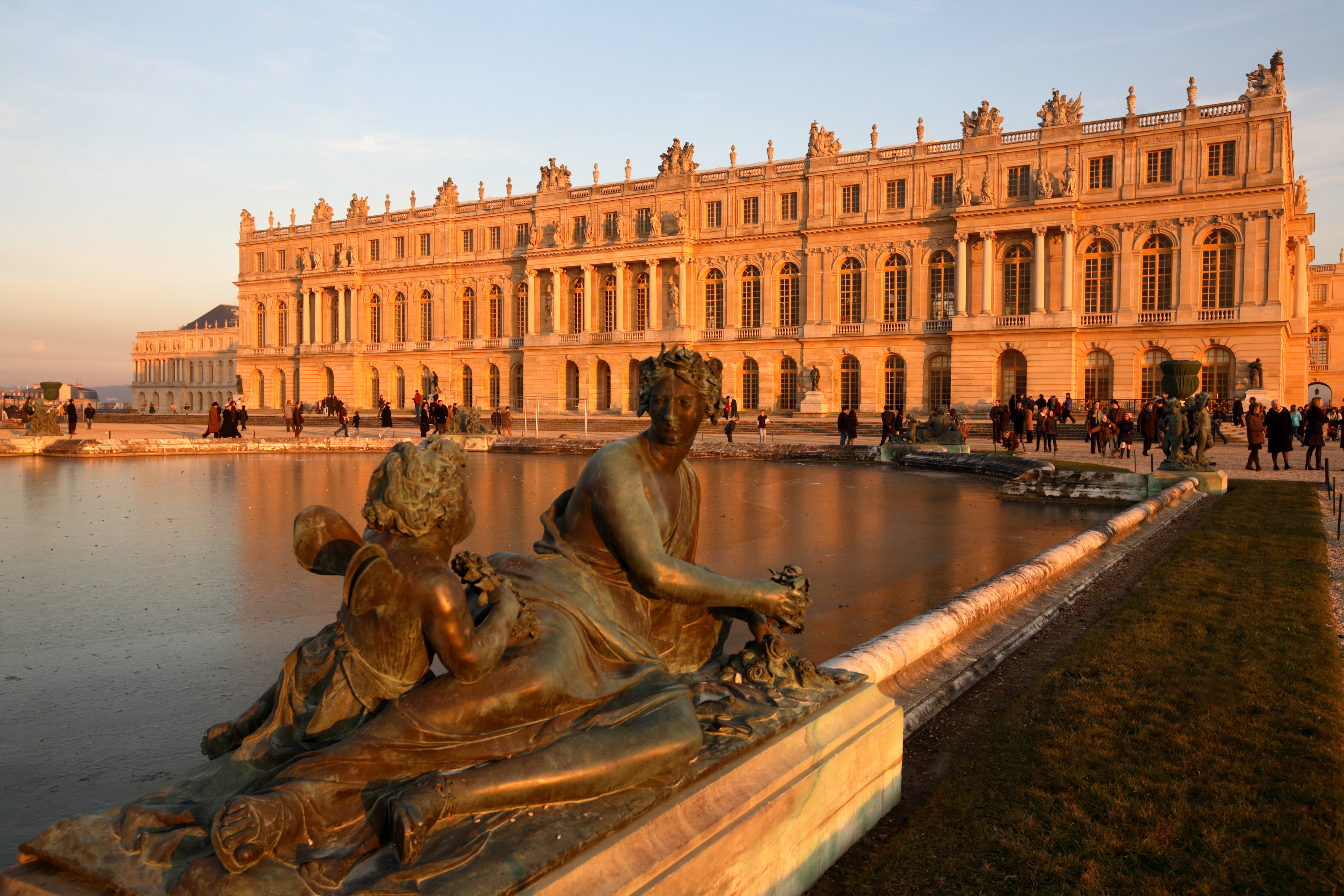 Bronze statue decorating Water Parterres with Chateau of Versailles in background.