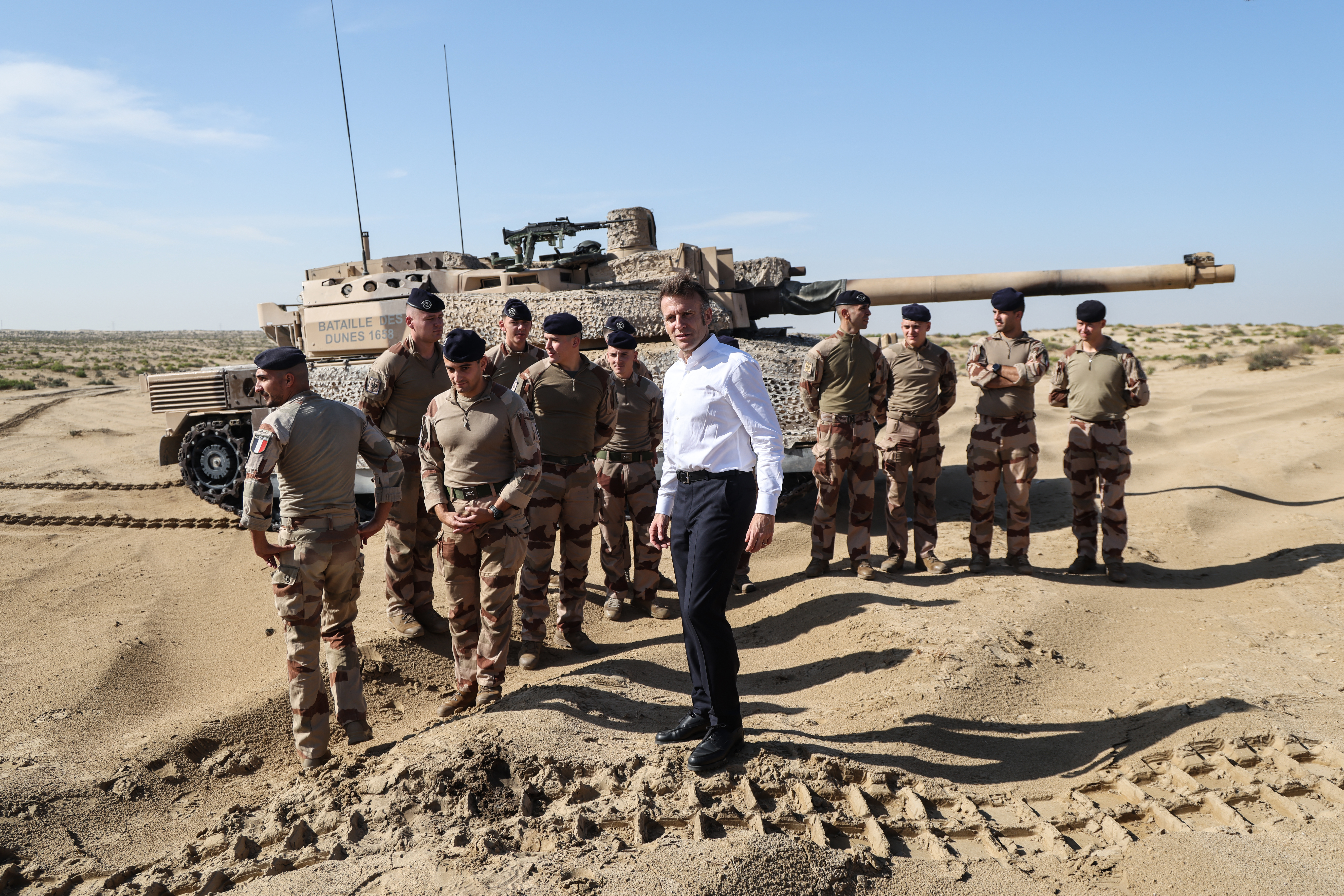 France's President Emmanuel Macron poses with French soldiers in front of a Leclerc tank during a troop?maneuver exercise near the 5th Cuirassier Regiment's base in Zayed Military City on December 22, 2025. Macron arrived in the United Arab Emirates on December 21 to celebrate Christmas with French troops and to discuss bilateral ties with the Gulf state, as France hopes for more cooperation in its fight against drug trafficking. (Photo by Ludovic MARIN / AFP)