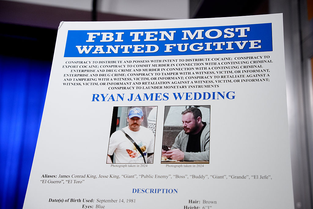 WASHINGTON, DC - NOVEMBER 19: A FBI Ten Most Wanted Fugitive poster is displayed during a news conference announcing the indictment of a former Olympic snowboarder Ryan Wedding, charging him with murder and money laundering in connection to a drug trafficking organization at the Justice Department on November 19, 2025 in Washington, DC. The Justice Department announced a fifteen-million-dollar reward for information leading to the arrest of Ryan James Wedding, the leader of a criminal drug organization who smuggled large quantities of cocaine through Colombia and Mexico for distribution in the United States and Canada. (Photo by Andrew Harnik/Getty Images)