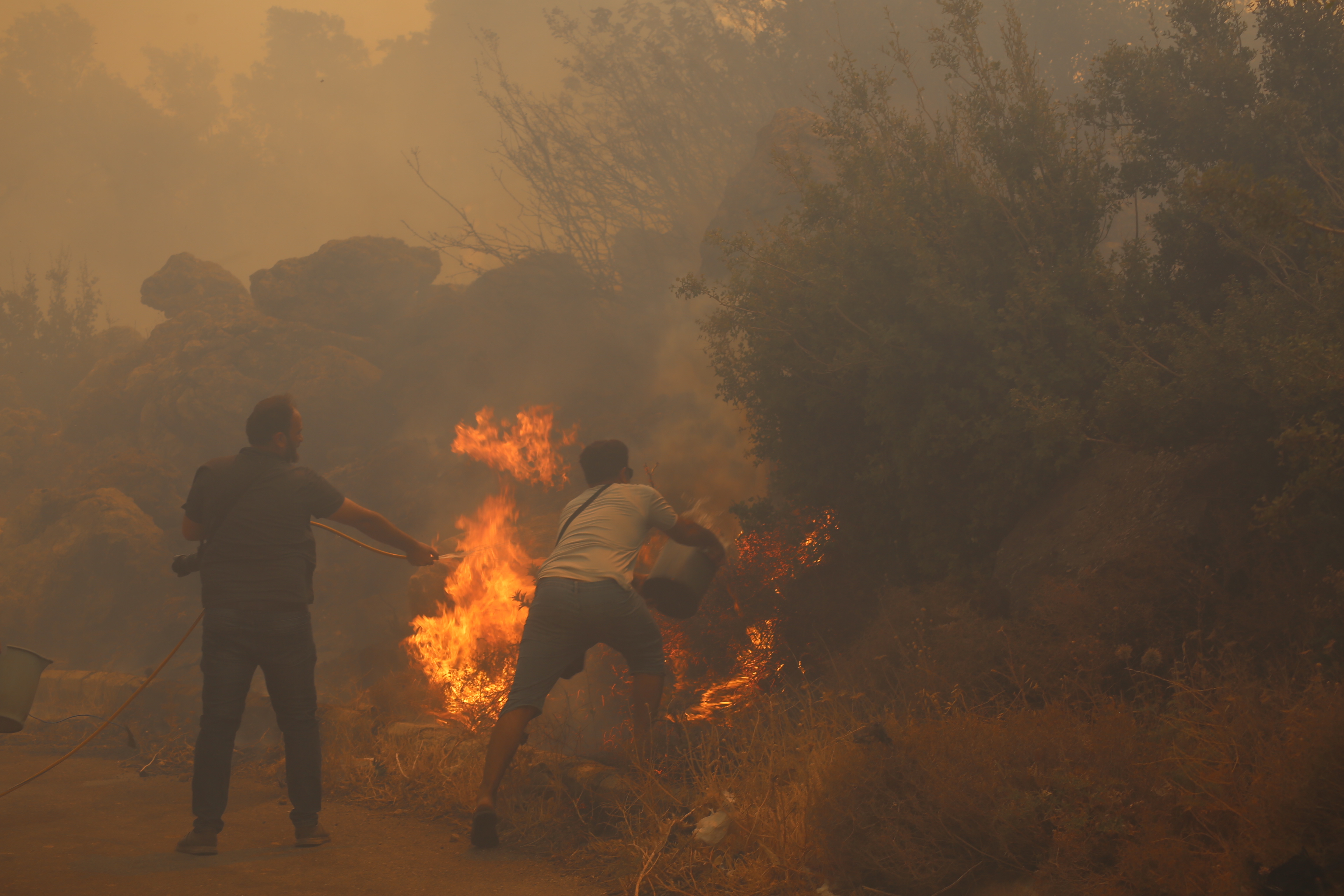 Bombeiros e moradores combatem incêndios florestais na planície de al-Ghab, na zona rural de Hama, em meio a uma onda de calor extremo que atingiu várias províncias do país