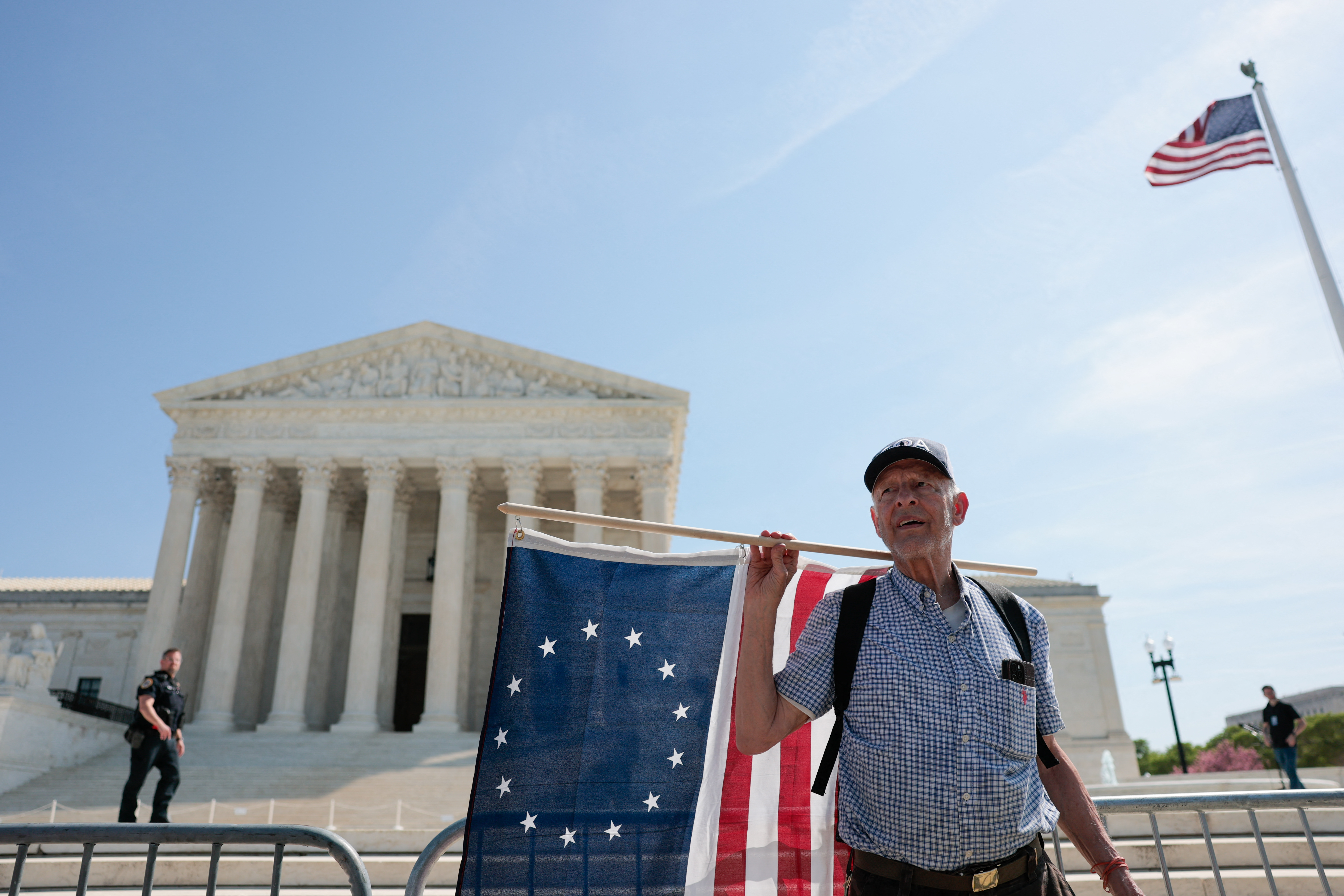 Um homem segura uma bandeira Betsy Ross, um modelo de 1792 da bandeira dos EUA, em frente à Suprema Corte dos EUA em Washington, DC, em 1º de abril de 2026