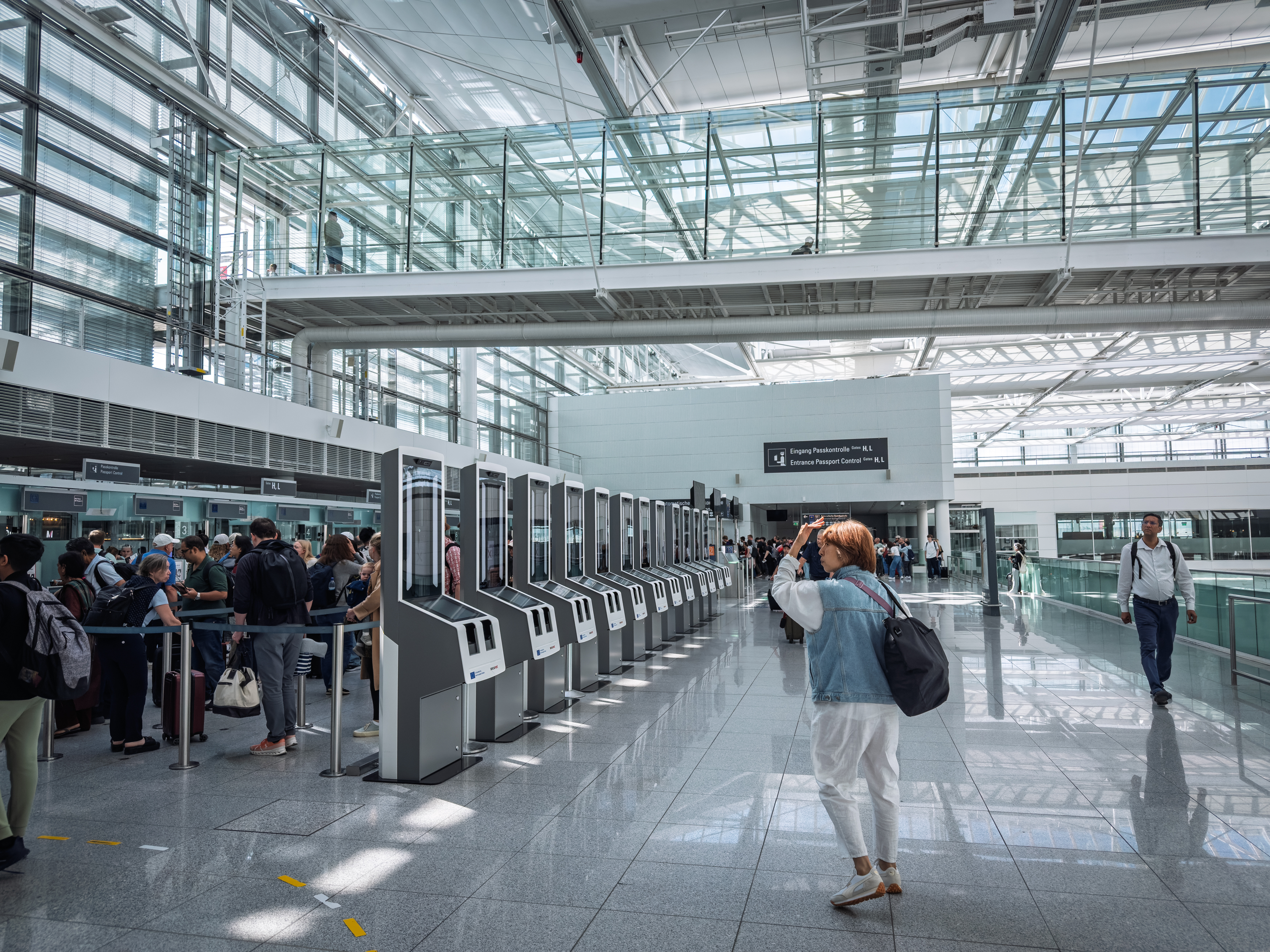 Self-service EES scanners at passport control in Munich Airport ready for the EU Entry Exit System. Travelers queue by biometric kiosks for automated identity checks.