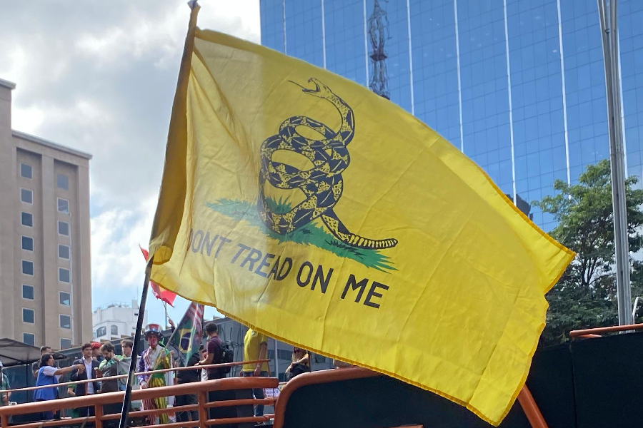 Manifestante hasteia bandeira de Gadsden, associada à ideologia libertária e anarcocapitalista, durante ato da direita realizado na Avenida Paulista, em São Paulo, em 1º de Maio de 2026