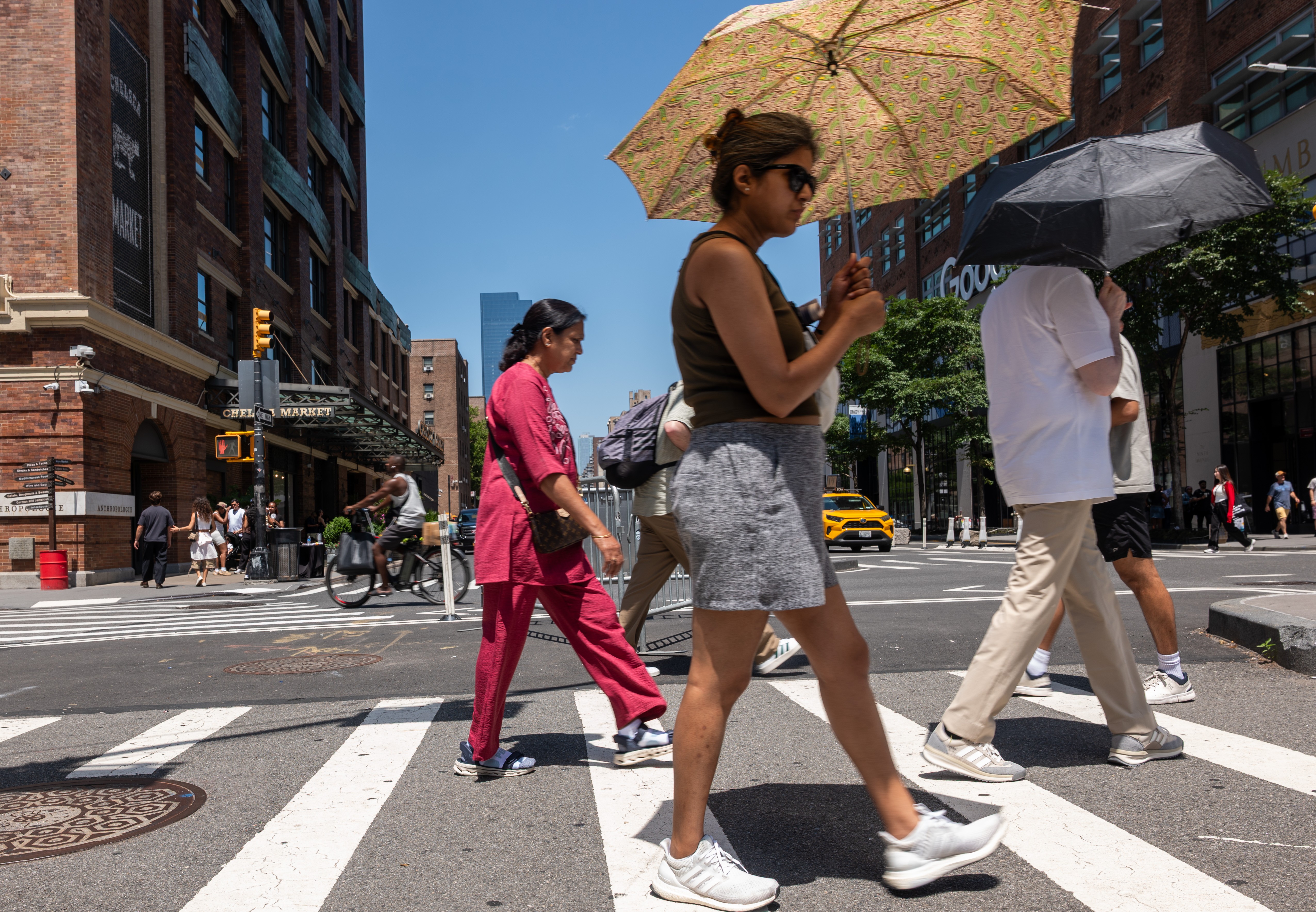 Pedestres usam guarda-chuvas para se proteger do sol durante a onda de calor que atinge Manhattan. A cidade de Nova York emitiu alerta para temperaturas acima de 38°C