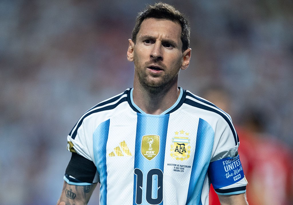 Lionel Messi, jogador de futebol, em close-up, vestindo a camisa branca e azul-claro da Argentina com o número 10, olhando para frente com expressão séria