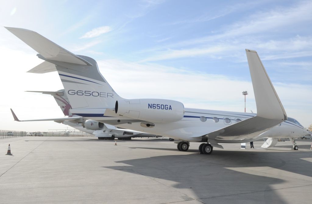 Jato executivo branco Gulfstream G650ER, matrícula N650GA, estacionado em uma pista de aeroporto sob céu azul claro com nuvens esparsas