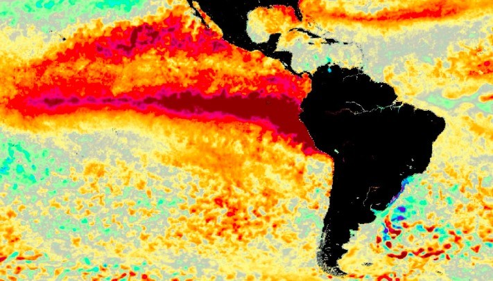 Mapa térmico do Oceano Pacífico e Américas, mostrando o fenômeno El Niño. A América do Sul e Central aparecem em preto. Uma faixa vermelha intensa, indicando águas mais quentes, se estende horizontalmente pelo Pacífico, acima da linha do Equador. Cores laranja e amarela representam temperaturas intermediárias, enquanto tons de azul e verde indicam águas mais frias, visíveis em algumas áreas próximas à costa sul-americana
