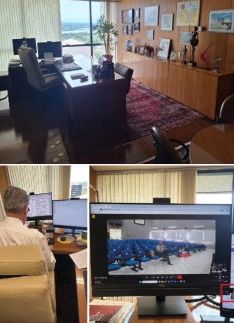Escritório com mesa de trabalho, estante de madeira com quadros e tapete persa. Abaixo, um homem de costas em frente a dois monitores e outro monitor exibindo uma sala de reunião vazia
