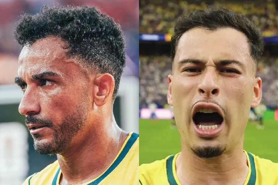 Dois jogadores de futebol, ambos com camisas amarelas e detalhes verdes. À esquerda, um homem de perfil, com barba e cabelo crespo, suando. À direita, um homem de frente, com bigode e cavanhaque, boca aberta em grito, expressão de raiva ou frustração, em um estádio