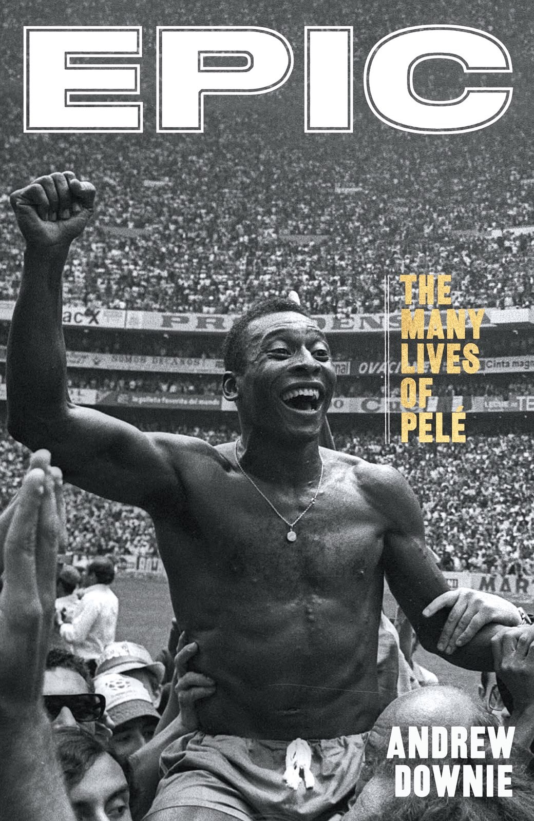 Pelé, sorrindo e sem camisa, é erguido por torcedores com o braço direito levantado em punho, celebrando em um estádio lotado. A imagem em preto e branco tem o título EPIC no topo e THE MANY LIVES OF PELE e ANDREW DOWNIE à direita