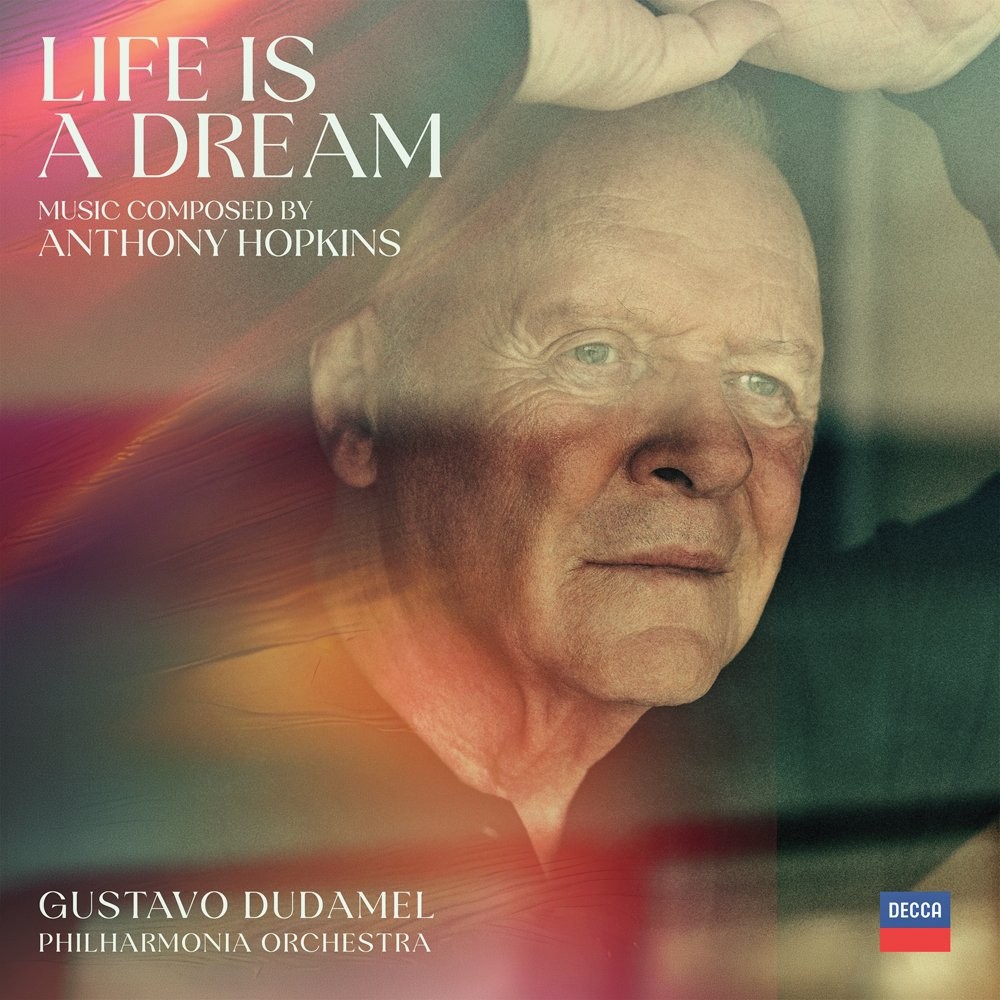 Capa do álbum Life is a Dream com Anthony Hopkins, um homem branco idoso com cabelo branco e olhos azuis, olhando para a direita com expressão pensativa. Ele tem a mão direita sobre a cabeça, em um fundo abstrato com tons de roxo, laranja e verde. O texto indica música composta por Anthony Hopkins, com Gustavo Dudamel e Philharmonia Orchestra, e o selo Decca