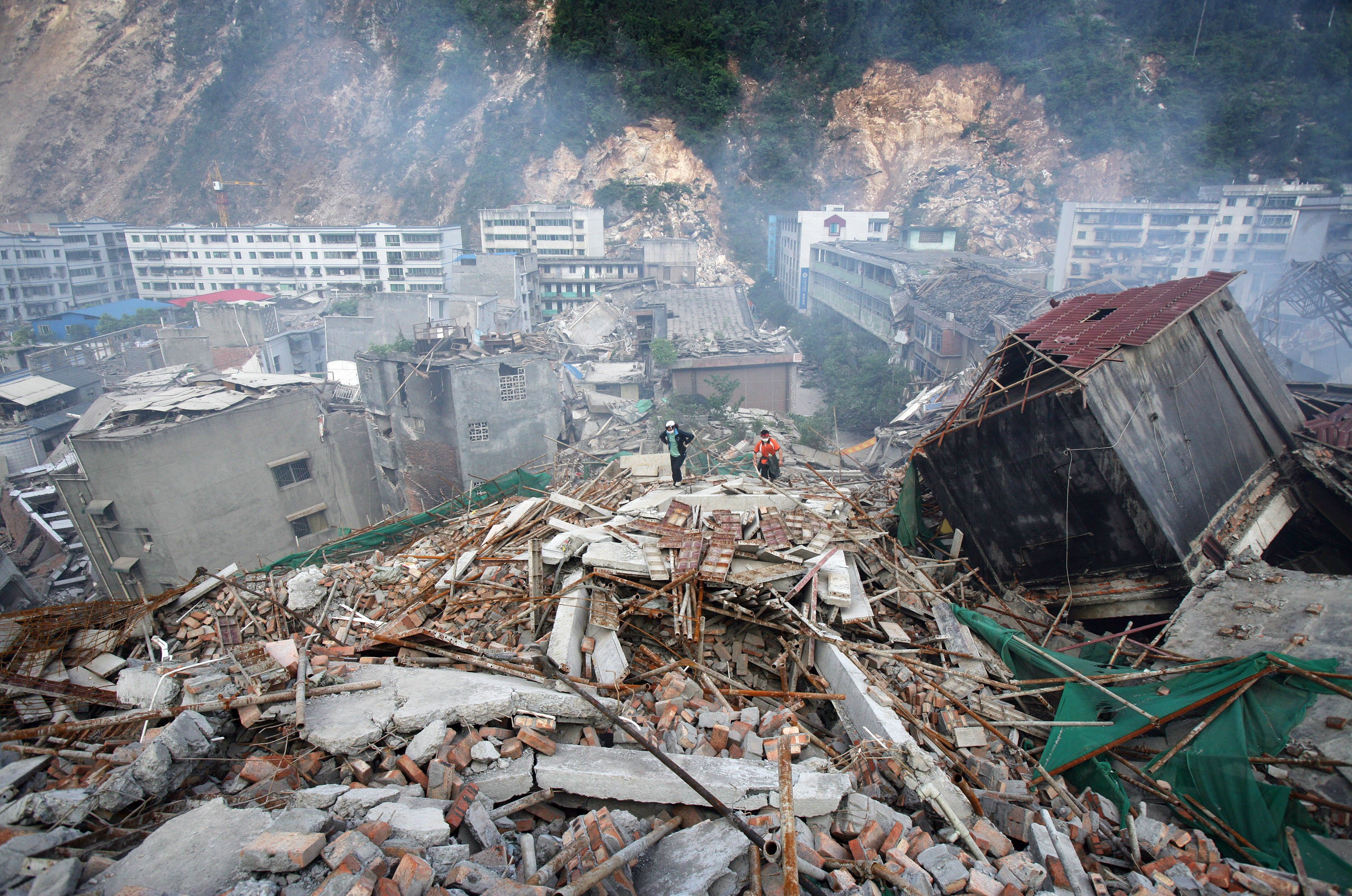 Sobreviventes de um terremoto caminham sobre os escombros de casas desabadas em busca de parentes, em 14 de maio de 2008, no condado de Beichuan, província de Sichuan, China