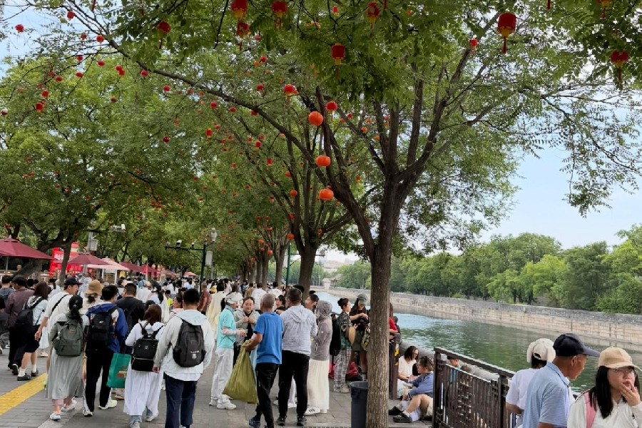 Pessoas aproveitam um espaço público arborizado e iluminado por lanternas na China, exemplo de uma visão de cidade em que mobilidade e planejamento urbano partem das necessidades de quem circula e vive esses espaços