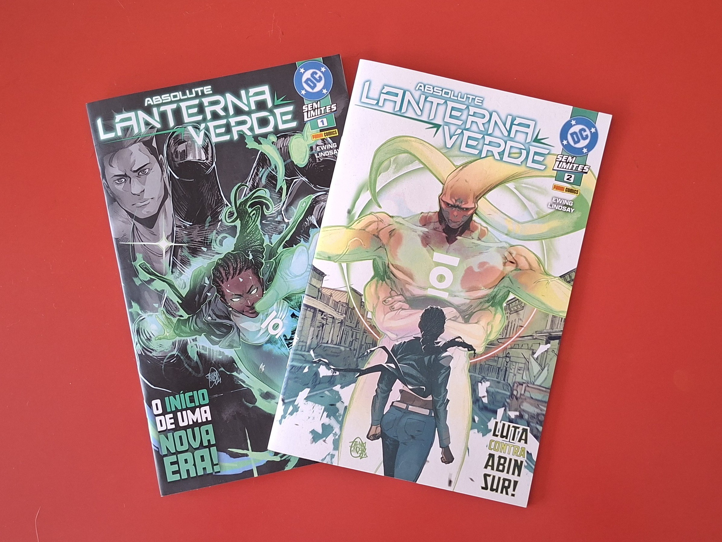 Duas capas de quadrinhos Absolute Lanterna Verde sobrepostas em fundo vermelho. A capa da esquerda, escura, mostra um homem e uma mulher negra com anel verde, cercados por energia. A capa da direita, clara, exibe um ser alienígena grande e uma mulher de costas, com texto Luta contra Abin Sur!.