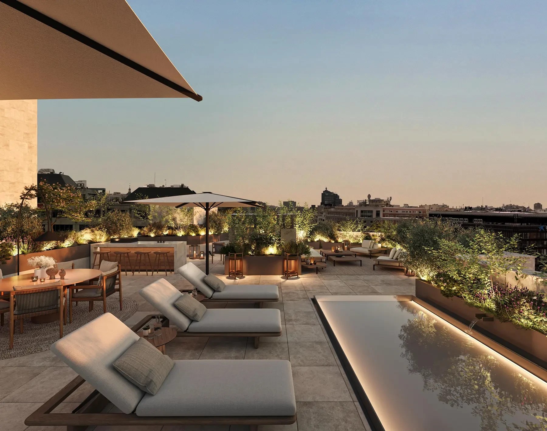 Terraço luxuoso ao entardecer com espreguiçadeiras claras, piscina retangular iluminada, bar de madeira, mesas e cadeiras, e vegetação exuberante em vasos, com vista para uma cidade ao fundo