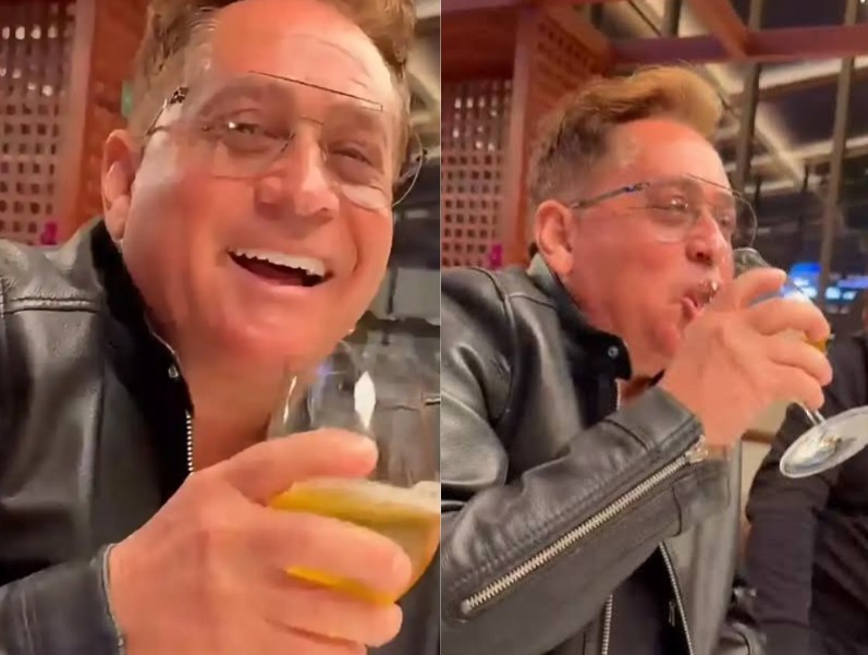 Homem de meia-idade, cabelo castanho claro, óculos e jaqueta de couro preta, sorri com a boca aberta na imagem da esquerda e bebe de uma taça de vinho na imagem da direita, em um ambiente interno