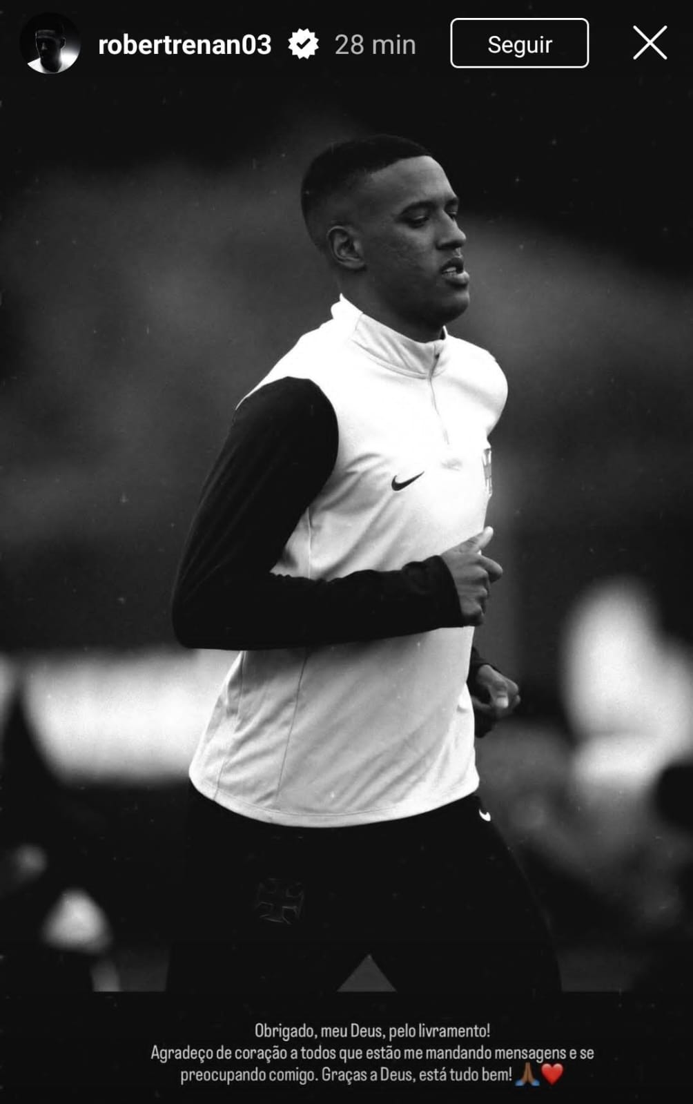 Jovem atleta de pele escura, cabelo curto, vestindo camisa de manga longa preta e colete branco, correndo com expressão séria em foto preto e branco. Texto na parte inferior: Obrigado, meu Deus, pelo livramento! Agradeço de coração a todos que estão me mandando mensagens e se preocupando comigo. Graças a Deus, está tudo bem!